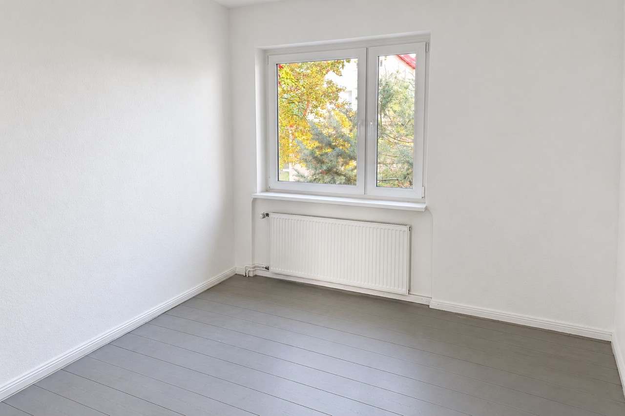 Zimmer mit grauen Dielen und Blick ins Grüne